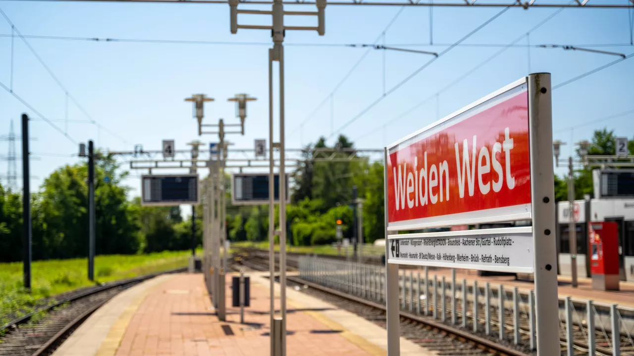 Haltestelle Weiden West Alternativtext Bild: Seitlicher Blick auf das Haltestellenschild Weiden West mit Schienen und Grünfläche im Hintergrund